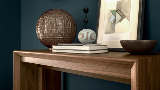 Goliath wooden console table with decorative items against a dark blue wall