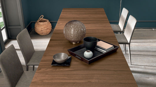 Goliath dining table set with chairs in a room with a textured wall and rug.