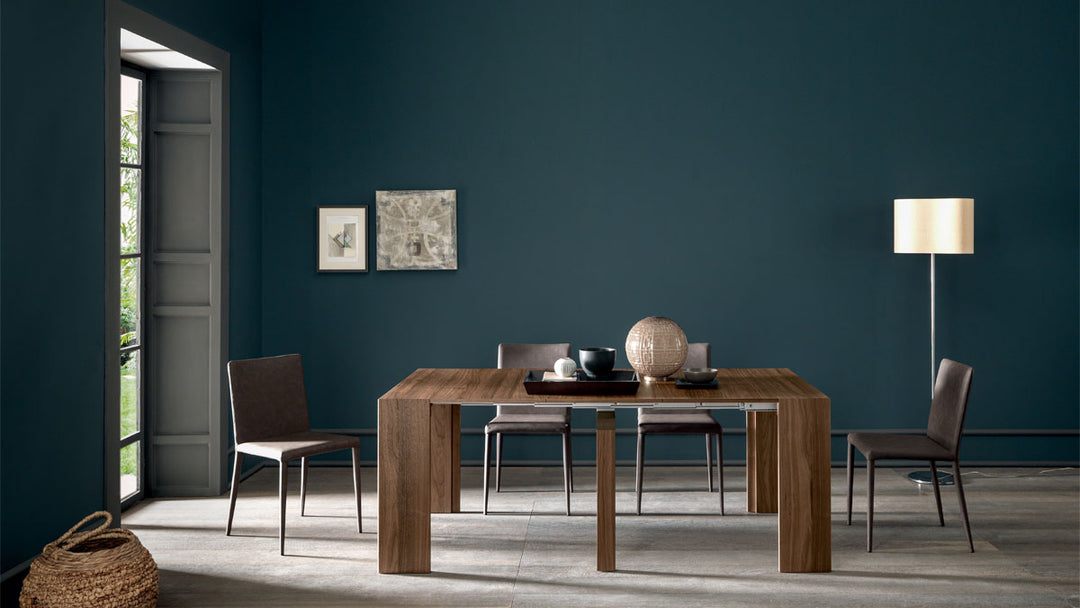 Goliath dining room with wooden table and chairs against a dark blue wall.