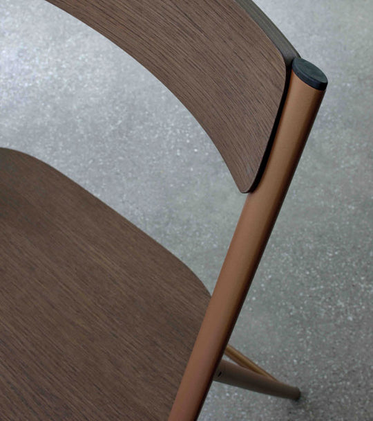 Close-up of a wooden Joe Wooden foldable dining chair with a brown frame on a light gray floor.