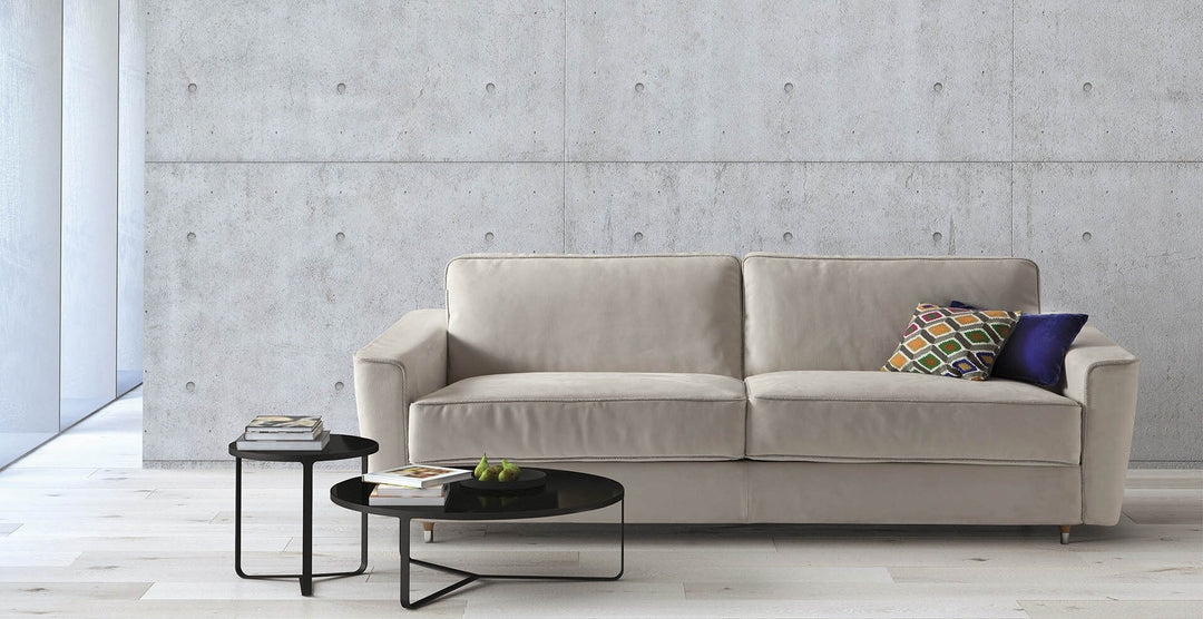 Beige Petrucciani sofa or sofa bed with decorative pillows in a modern living room setting.