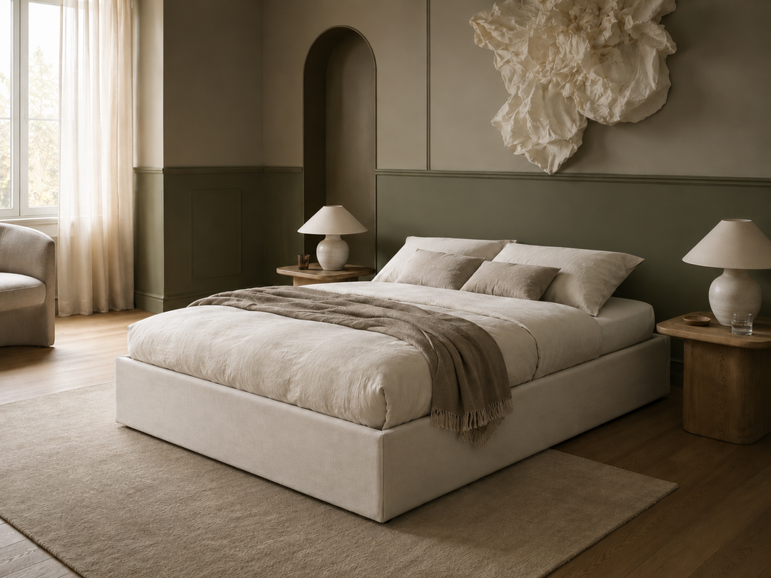 Ted a modern upholstered storage ottoman bed in a neutral-toned bedroom, featuring a low platform bed frame, cream bedding, a taupe throw blanket, matching side tables with white table lamps, and a textured beige rug.
